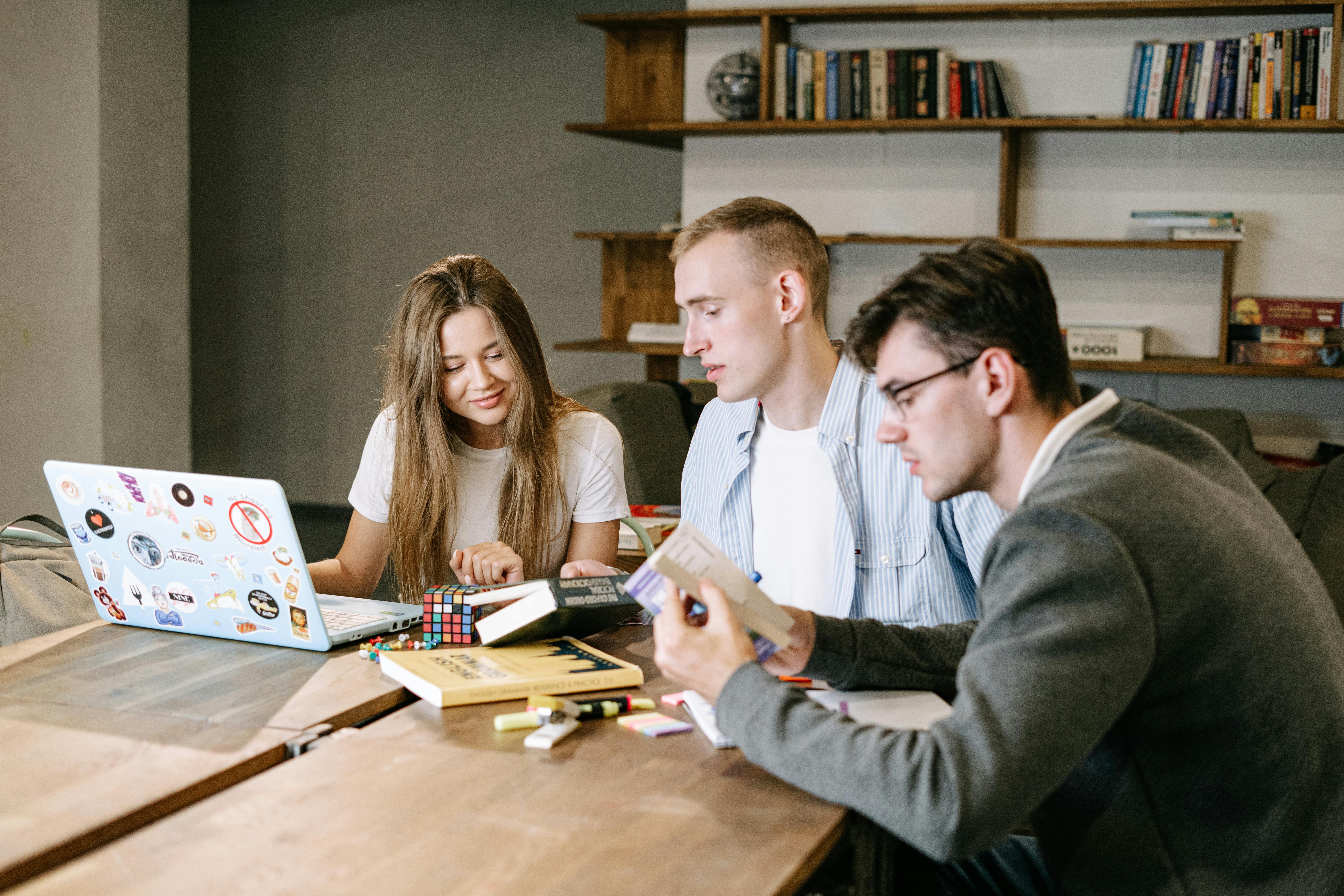a group of people sitting at a table looking at a laptop