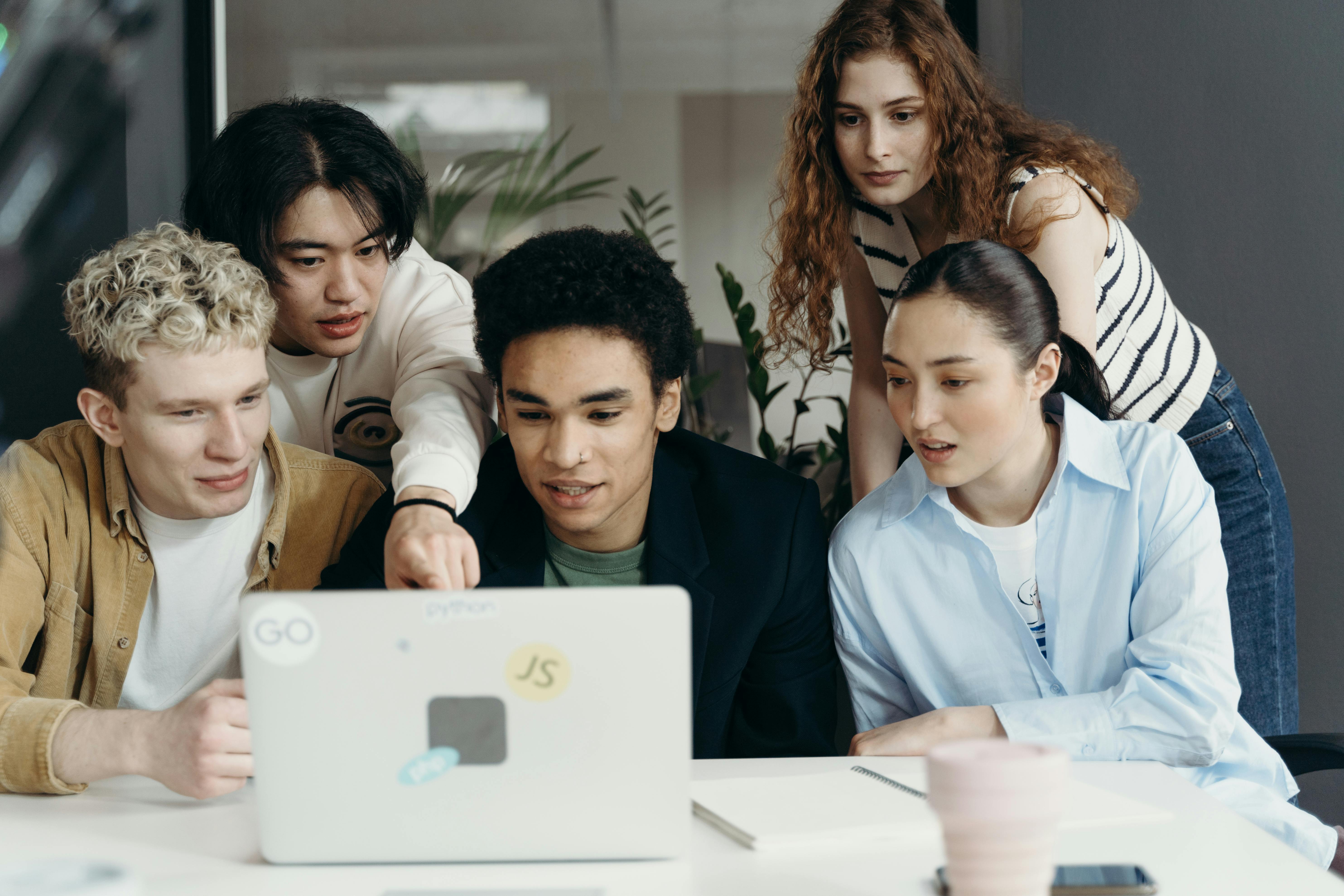 a group of people looking at a laptop