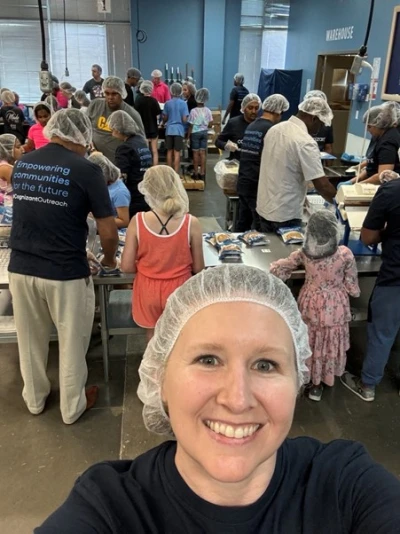 a person taking a selfie in a room with persony people in hair nets