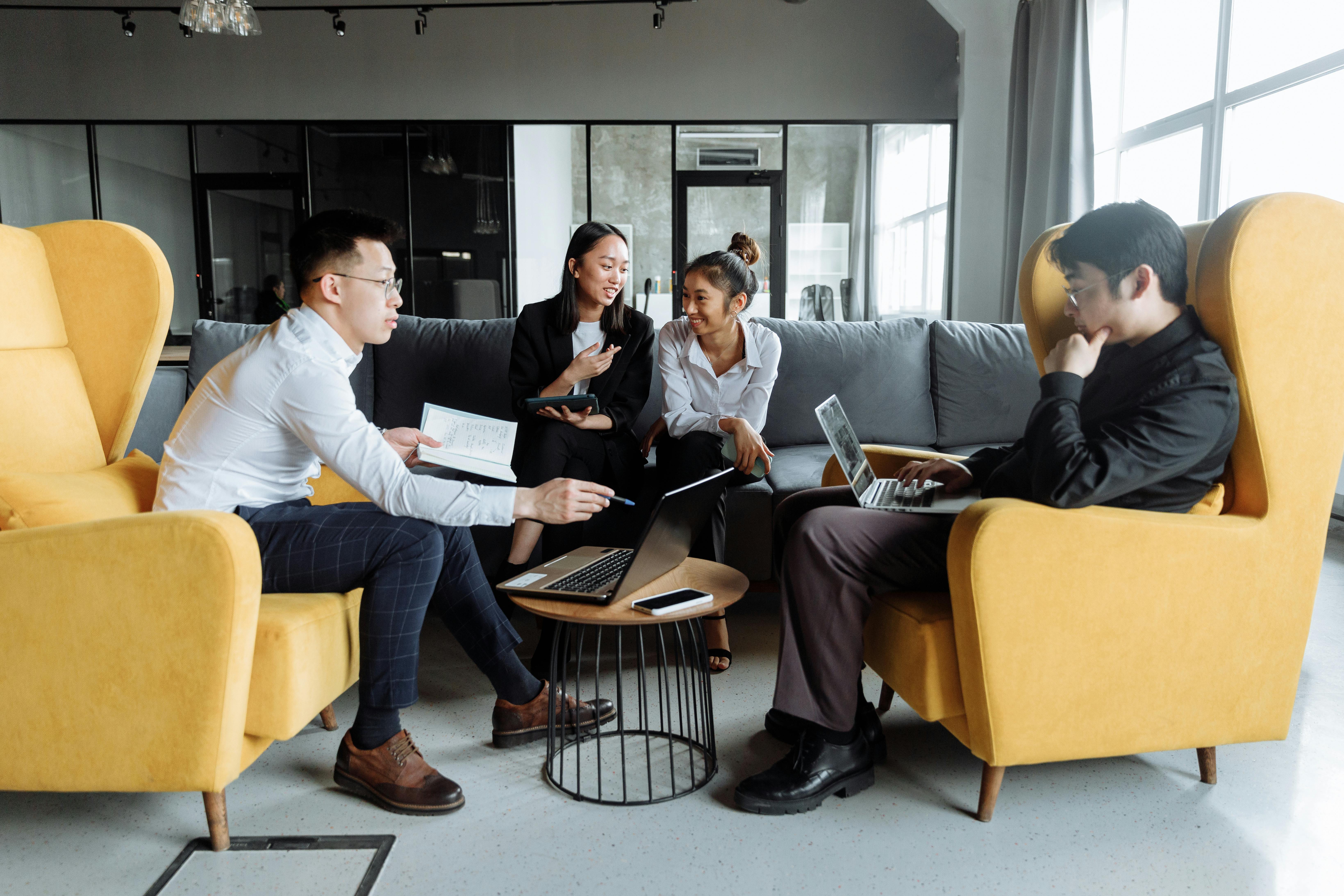 a group of people sitting around a table with laptops